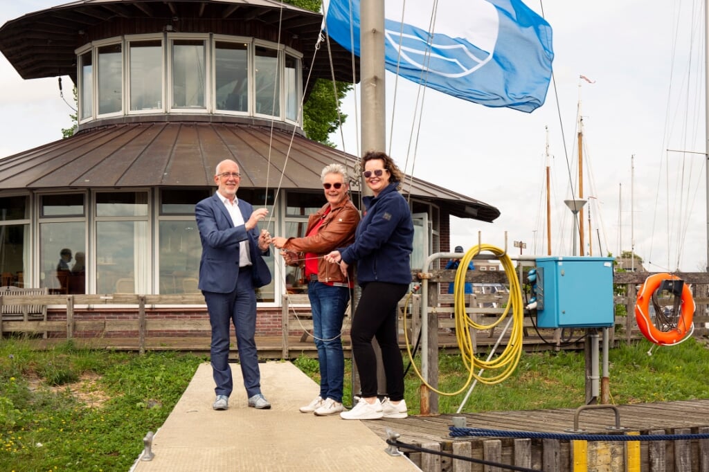 Gerrit Knol hijst de Blauwe Vlag met havenmeester Hilda Verwer en Annegreeth Steinbach (De Kranerweer). .