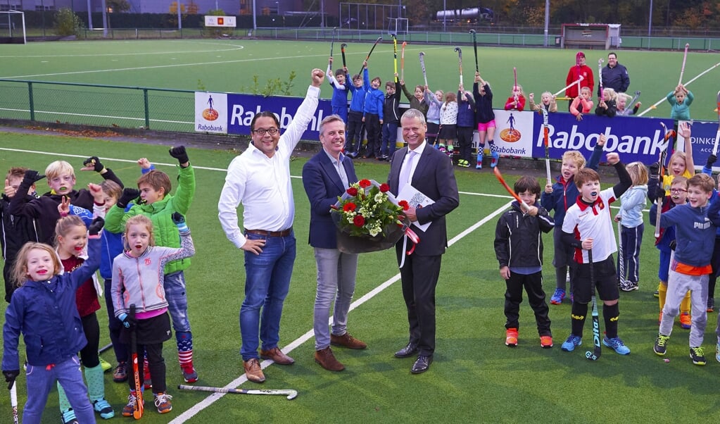 Maarten Plasmans, Erik van de Vijver en Remco Kuipéri (rechts) vieren met de jeugd van HTC hockey het nieuwe sponsorcontract