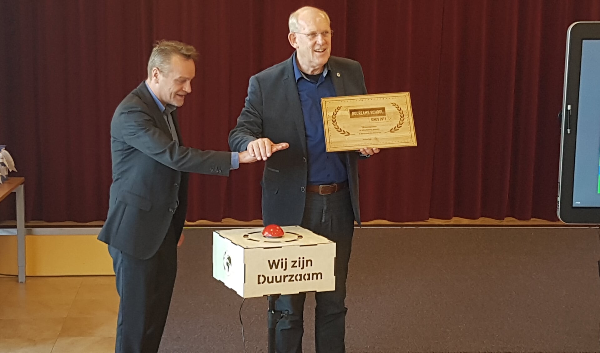 Wethouder Paul van Liempd (links)  en John van Dijen directeur Emiliusschool drukken op de rode knop