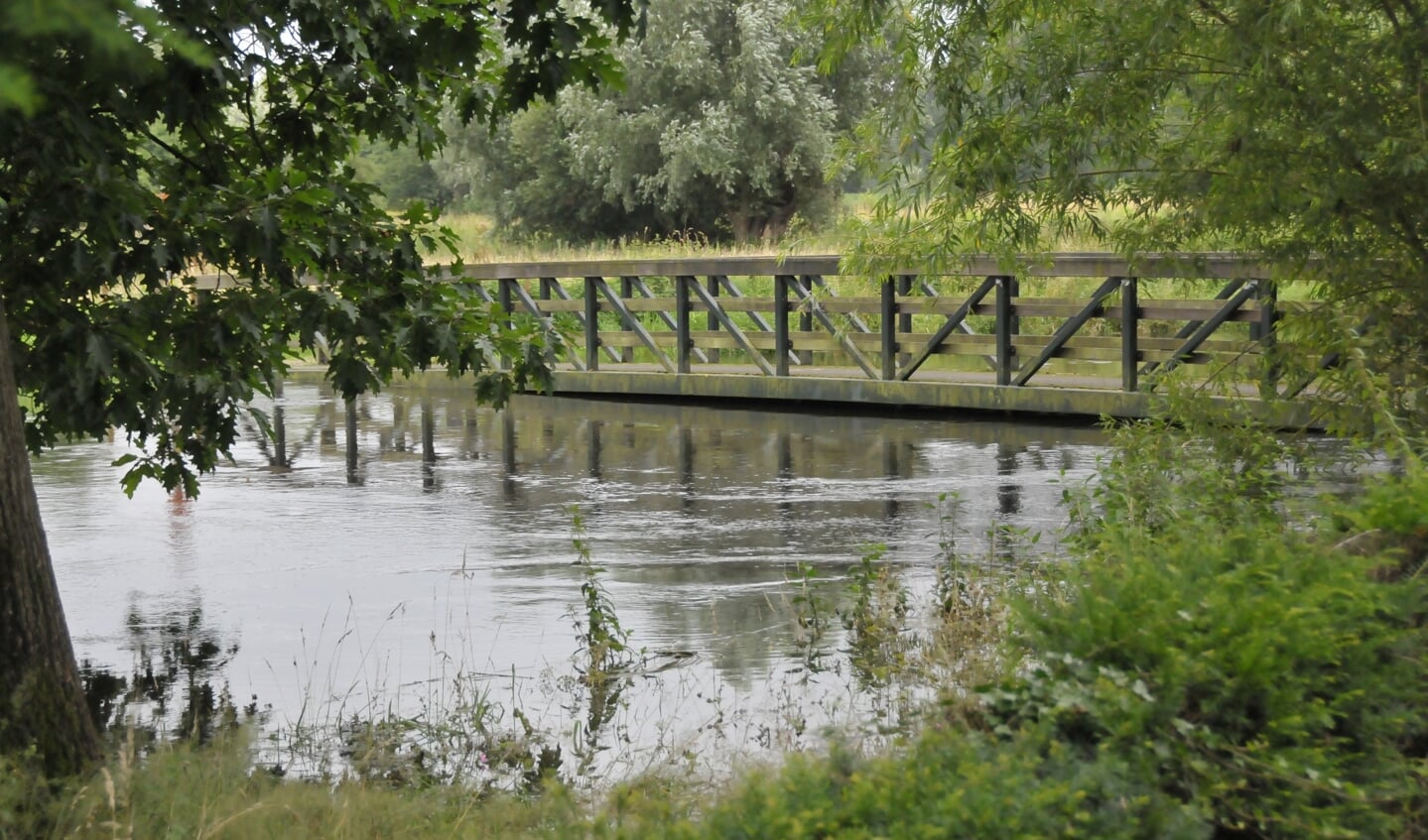 Het water staat hoog in de Dommel. Voetgangersbrug Vroonhoven park raakt  bijna het water