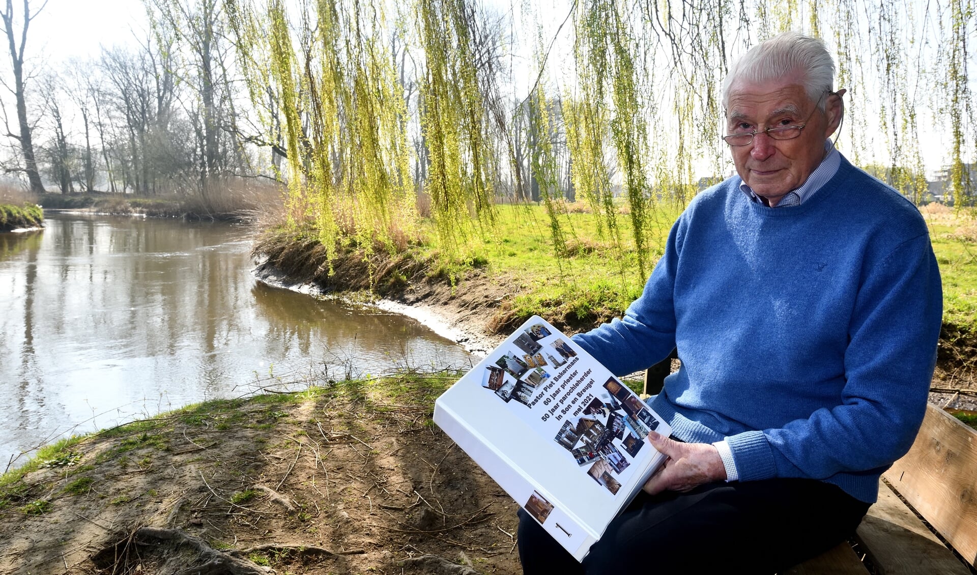 Piet Bakermans met een van de boeken op het bankje bij de Dommel