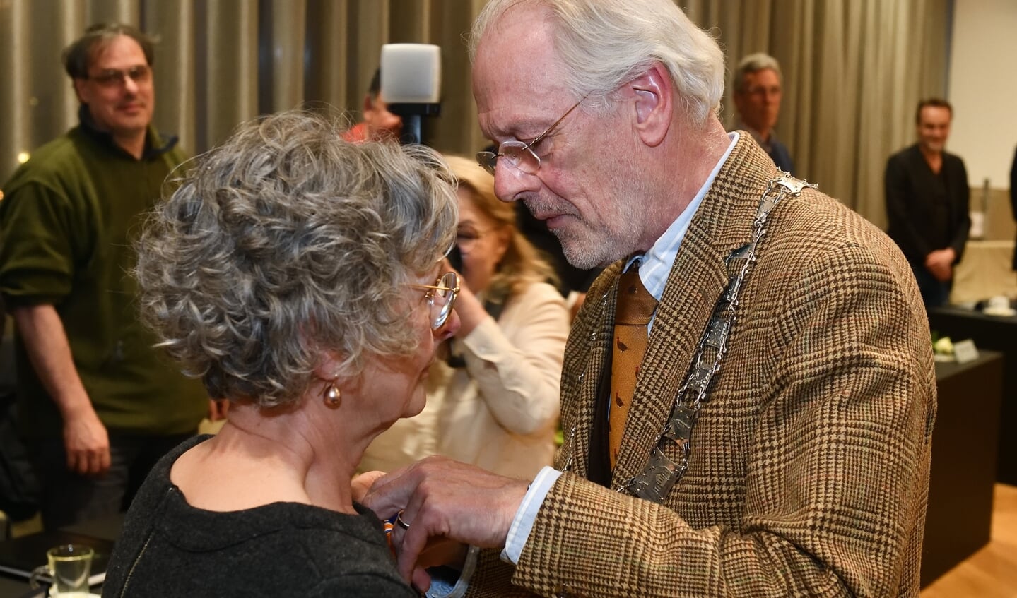 Burgemeester Hans Gaillard speldt de versierselen op bij Elly Brocken