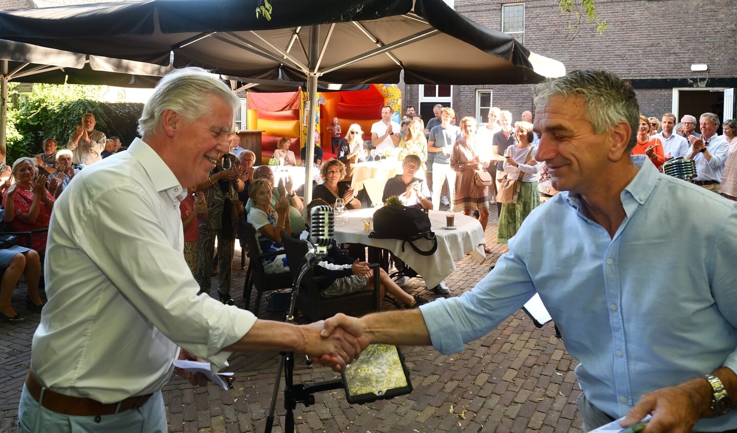 Stan Mooij (links) overhandigt het eerste exemplaar van zijn dichtbundel aan wethouder Jos de Bruin.