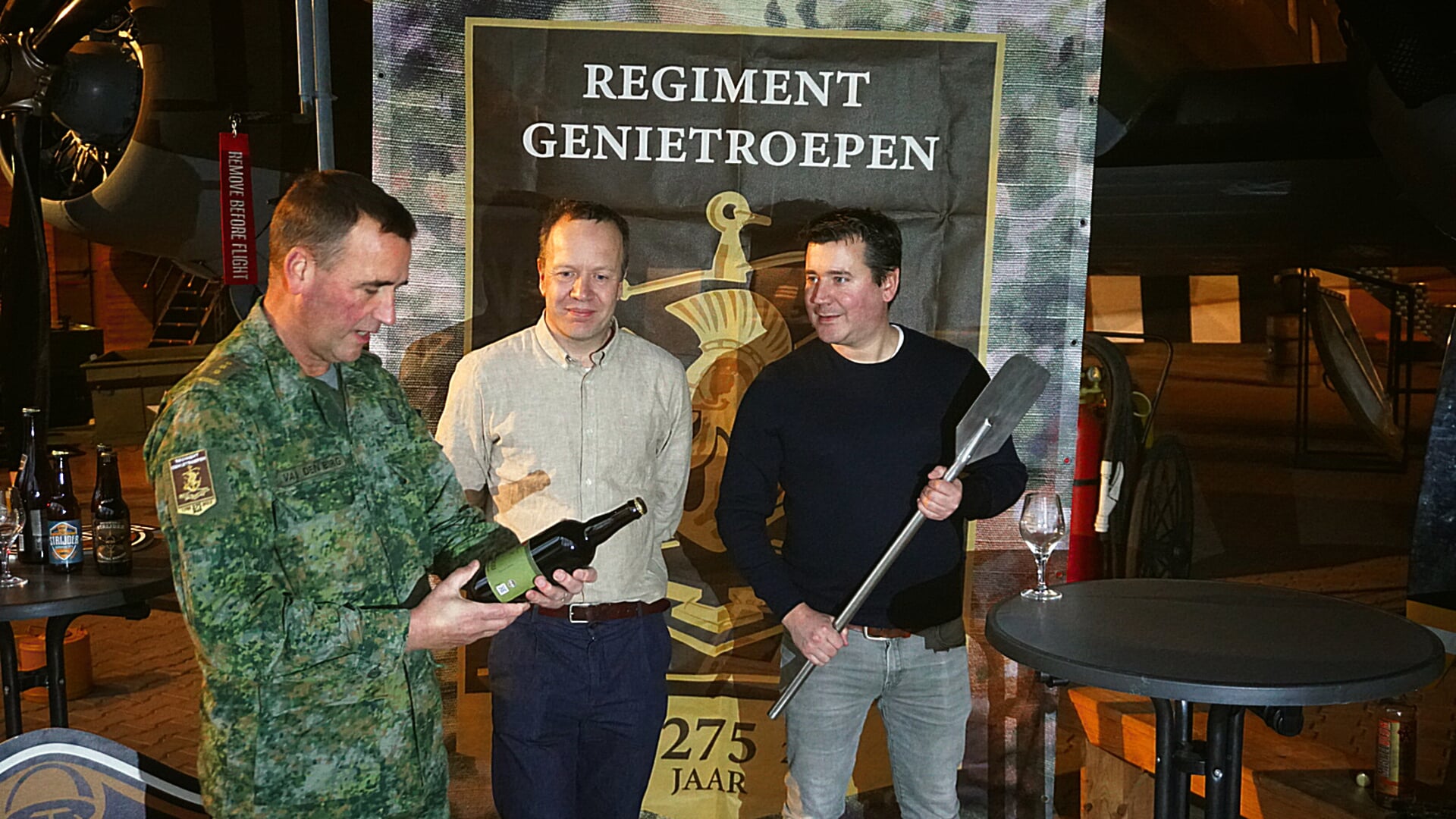 Kolonel Bas van den Berg ontvangt de eerste fles bier Sodeju!
