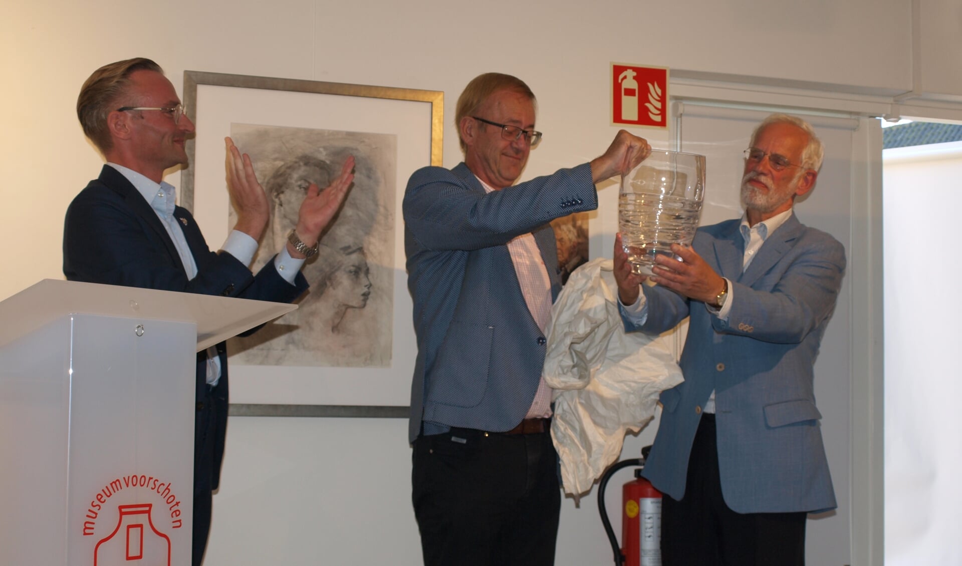 Wethouder Nanning Mol reikt namens de gemeente Voorschoten de kristallen vaas met inscriptie uit aan de bestuursleden van de VKK, René Smittenaar (l) en Gert Both (r)