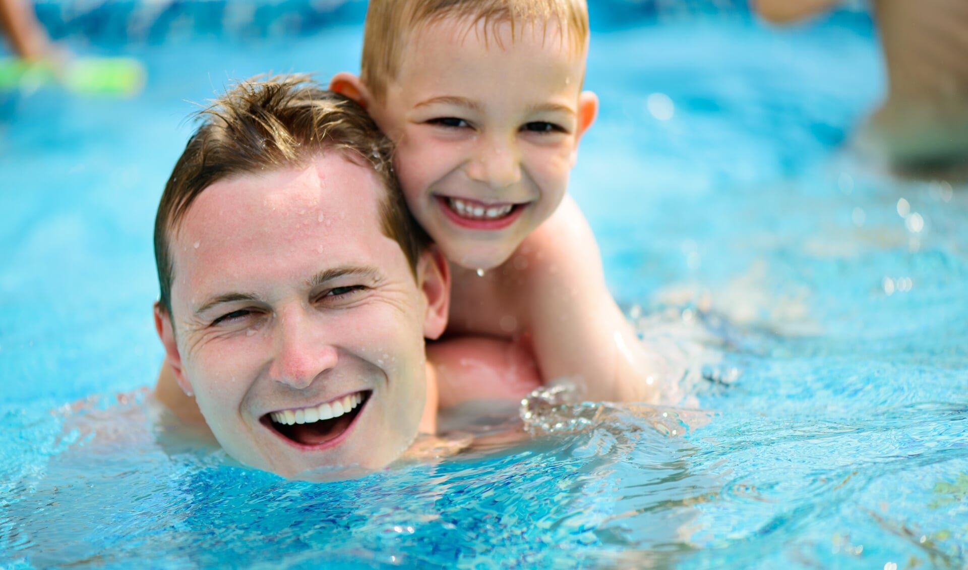 Young father with little son swimming in pool