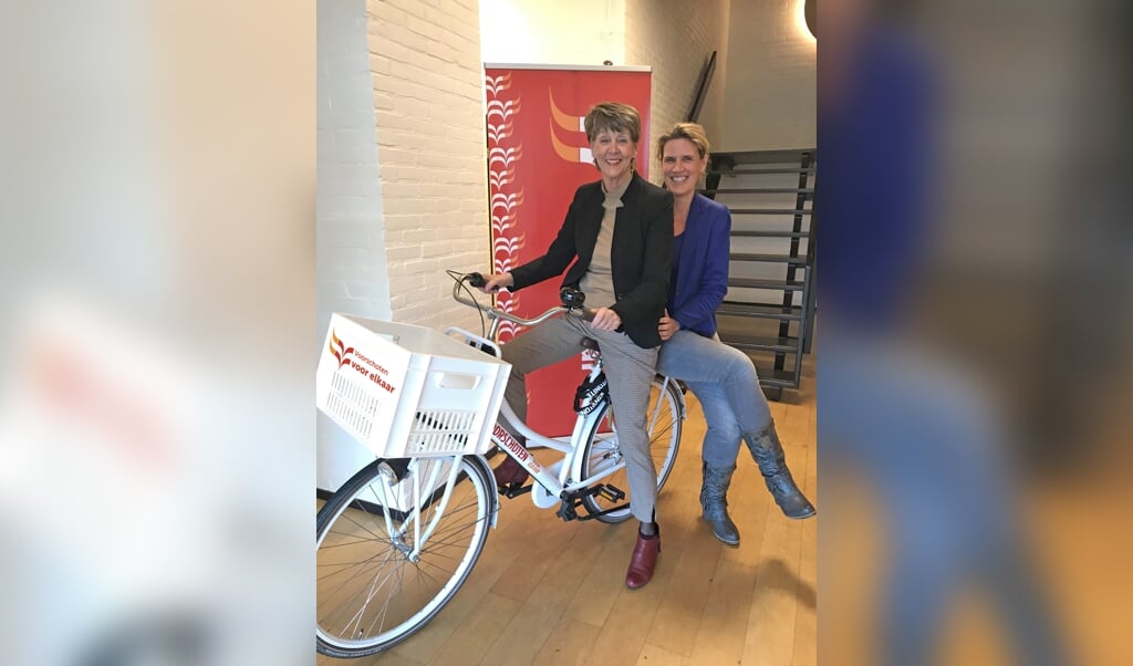 Ria van Vliet (l) vertrekt als directeur-bestuurder van Voorschoten Voor Elkaar. Haar opvolger Yvonne van Balen zit achterop. Foto: Voorschoten Voor Elkaar