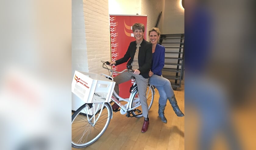 Ria van Vliet (l) vertrekt als directeur-bestuurder van Voorschoten Voor Elkaar. Haar opvolger Yvonne van Balen zit achterop. Foto: Voorschoten Voor Elkaar