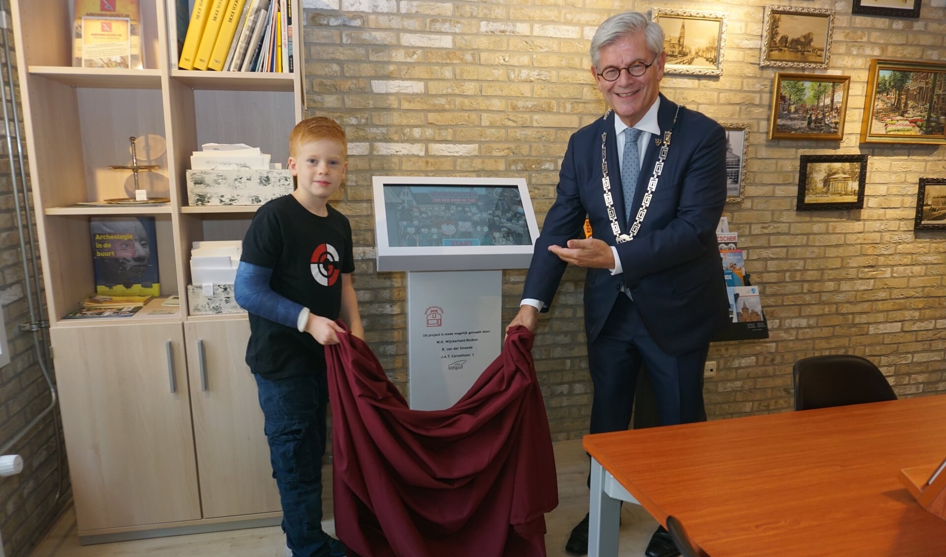 Burgemeester Charlie Aptroot onthult met kleinzoon Julius de tijdmachine in het museum Voorschoten