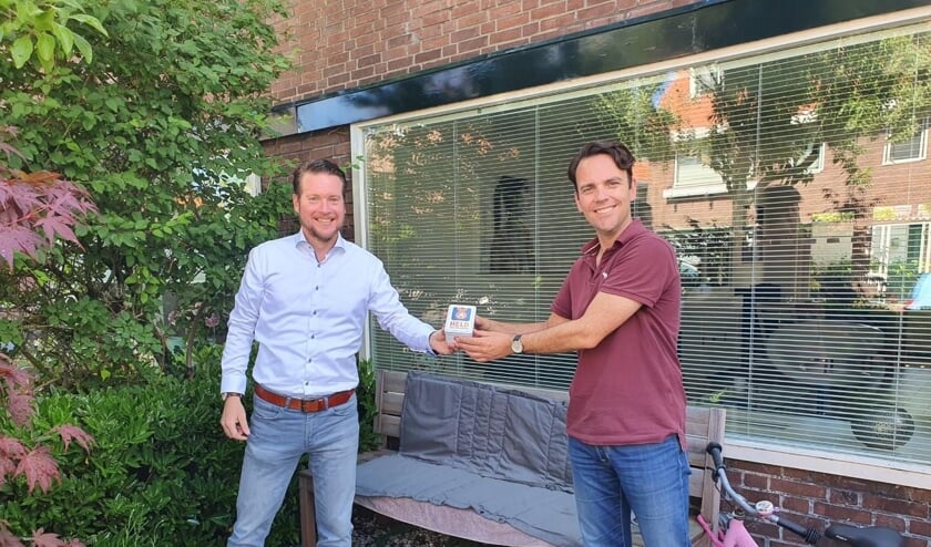 VVD-raadslid Bart Lavrijsen deelt de heldenwaardering uit aan Bob Sentrop, voorzitter Oranjevereniging Voorschoten. Foto: VVD Voorschoten