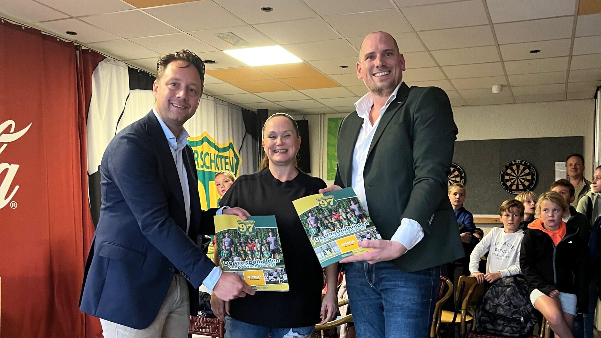 Wethouder Paul de Bruijn (l) en Tom van Vliet van de Jumbo met het nieuwe voetbalplaatjes album. 