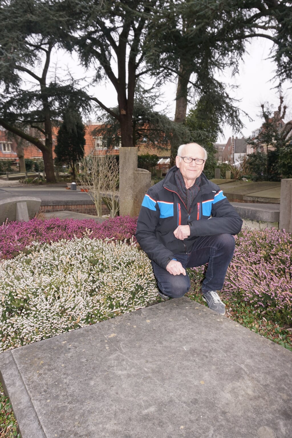 Mede-auteur 'Duizend jaar Dorpskerk' en bedenker van de digitale rondleiding op het Kerkhof achter de Dorpskerk Karel de Vries bij de deksteen op de ingang van de grafkelder van Van Duivenvoorde. Foto: VSK