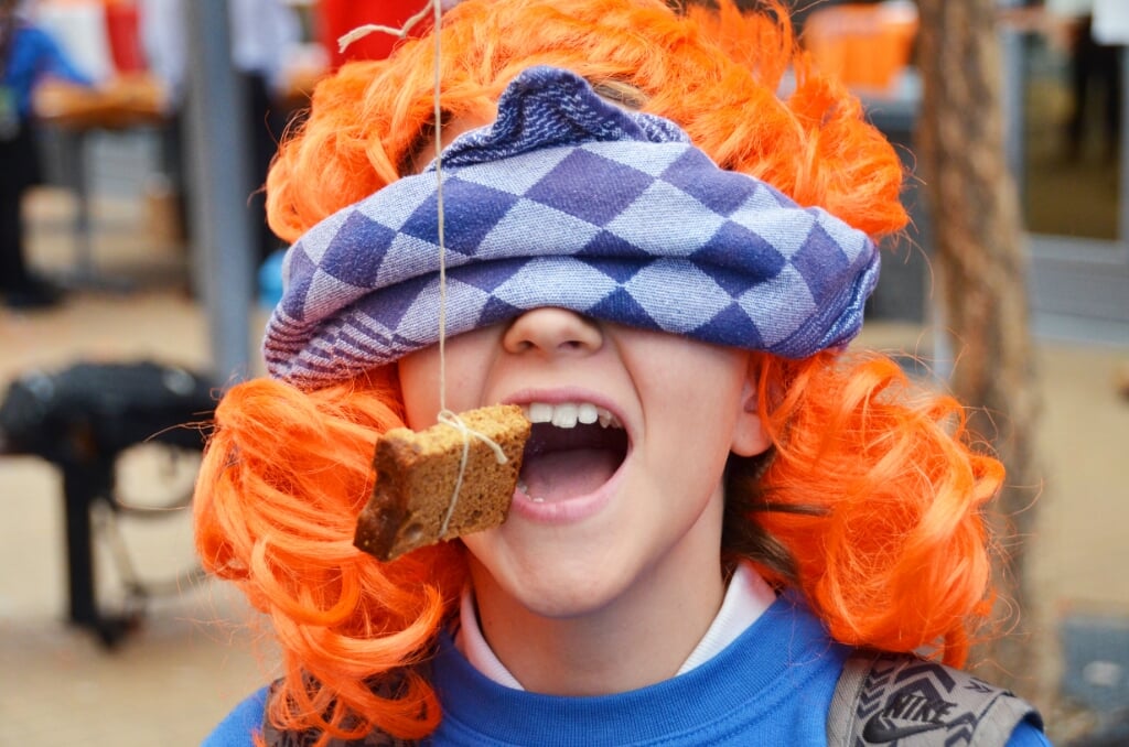A BSN student having fun on King's day with 'koekhappen', an old Dutch tradition for children which is still going on today. Dressed in orange of course, due to the name of the Royal family: Van Oranje. Photo: BSN