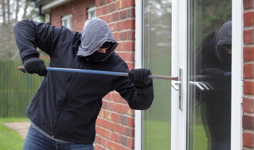 Burglar breaking into a house window with a crowbar