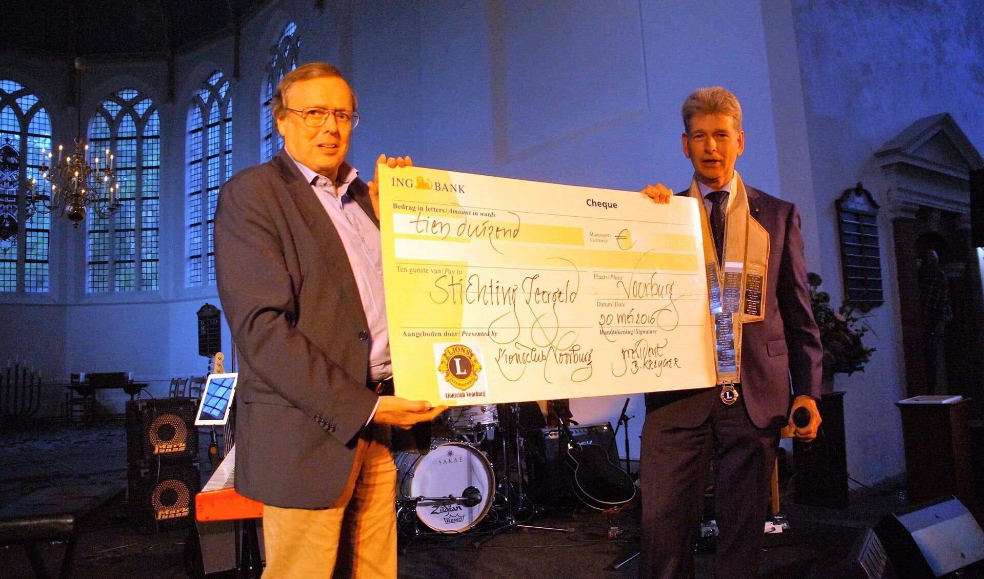 Bas Kreijger van Lions Club Voorburg reikt een cheque van € 10.000 uit aan Wim Schmale, voorzitter van het bestuur van de Stichting Leergeld (foto: PR).