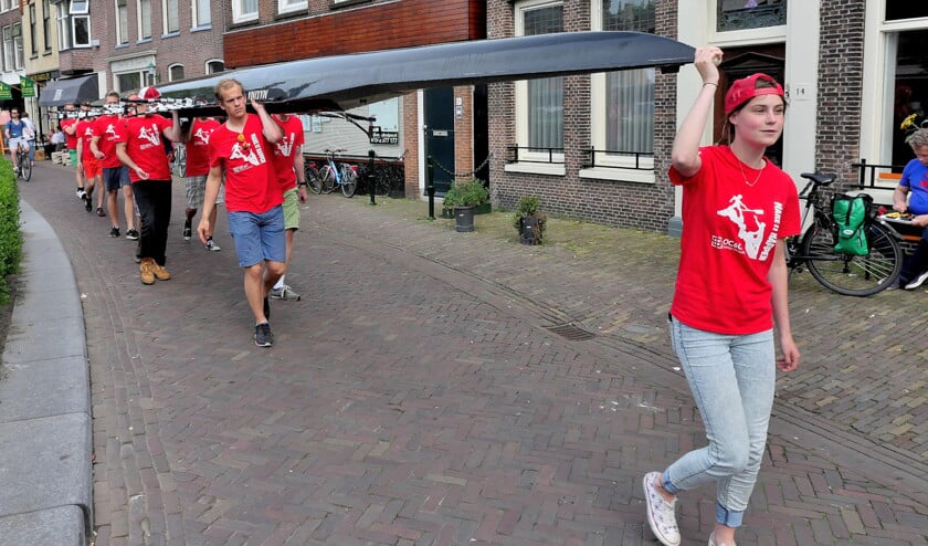 De boten kunnen niet door de sluis varen, dus ze worden door vrijwilligers uit het water gehaald en eromheen gedragen (archieffoto Het Krantje).