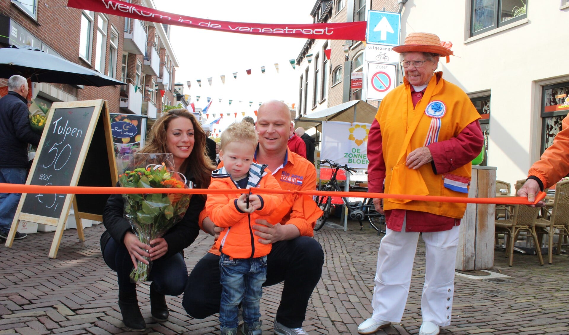 Thijs Brand, zoon van fietsenhandelaar Dennis Brand en zijn vrow Linda opende de rommelmarkt in de Venestrraat (foto: Dick Janssen).