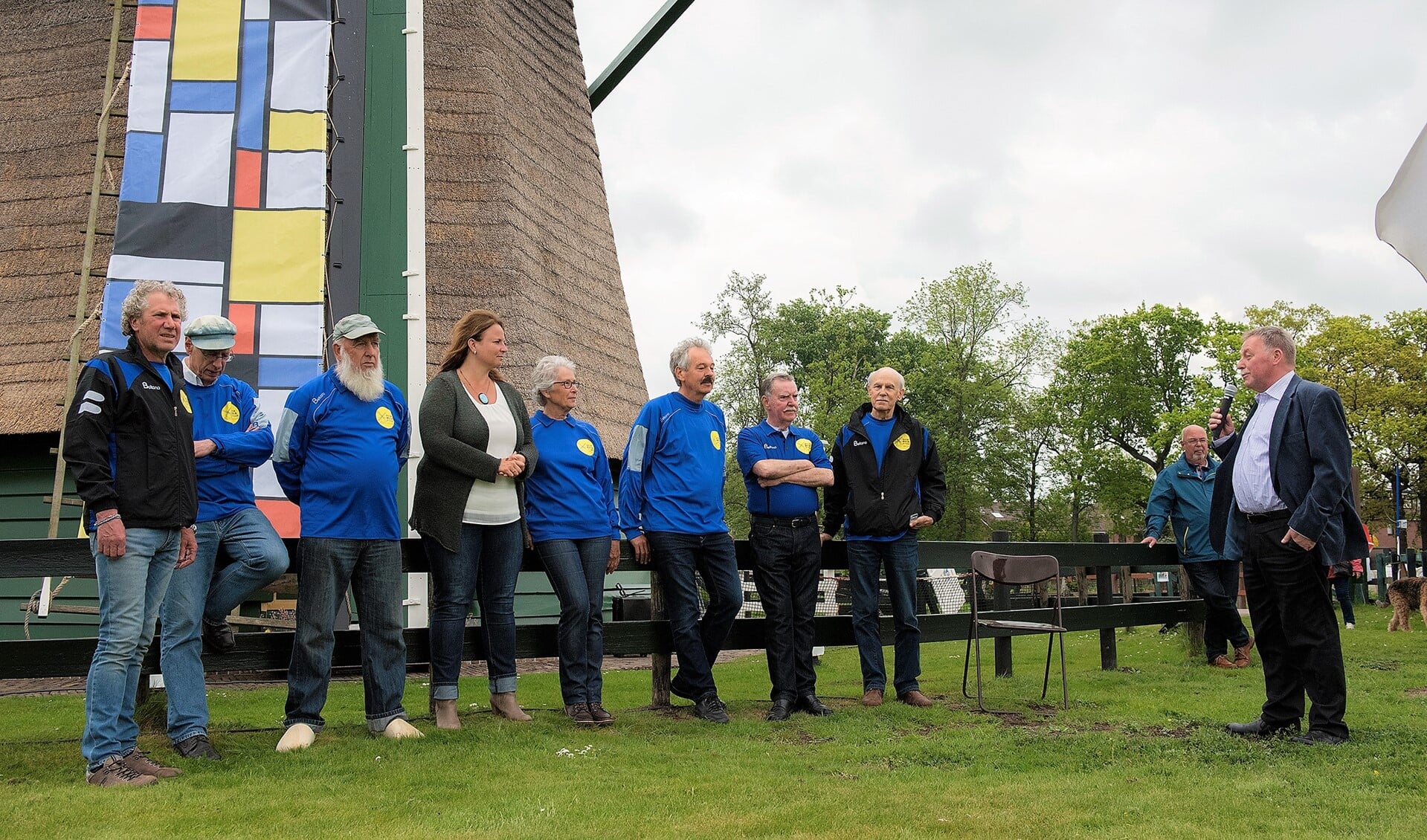 De vrijwilligers van De Vlieger in hun nieuwe gesponsorde kleding met wethouder Nadine Stemerdink bij de van Mondriaan motieven voorziene molenwieken  (foto: Michel Groen).