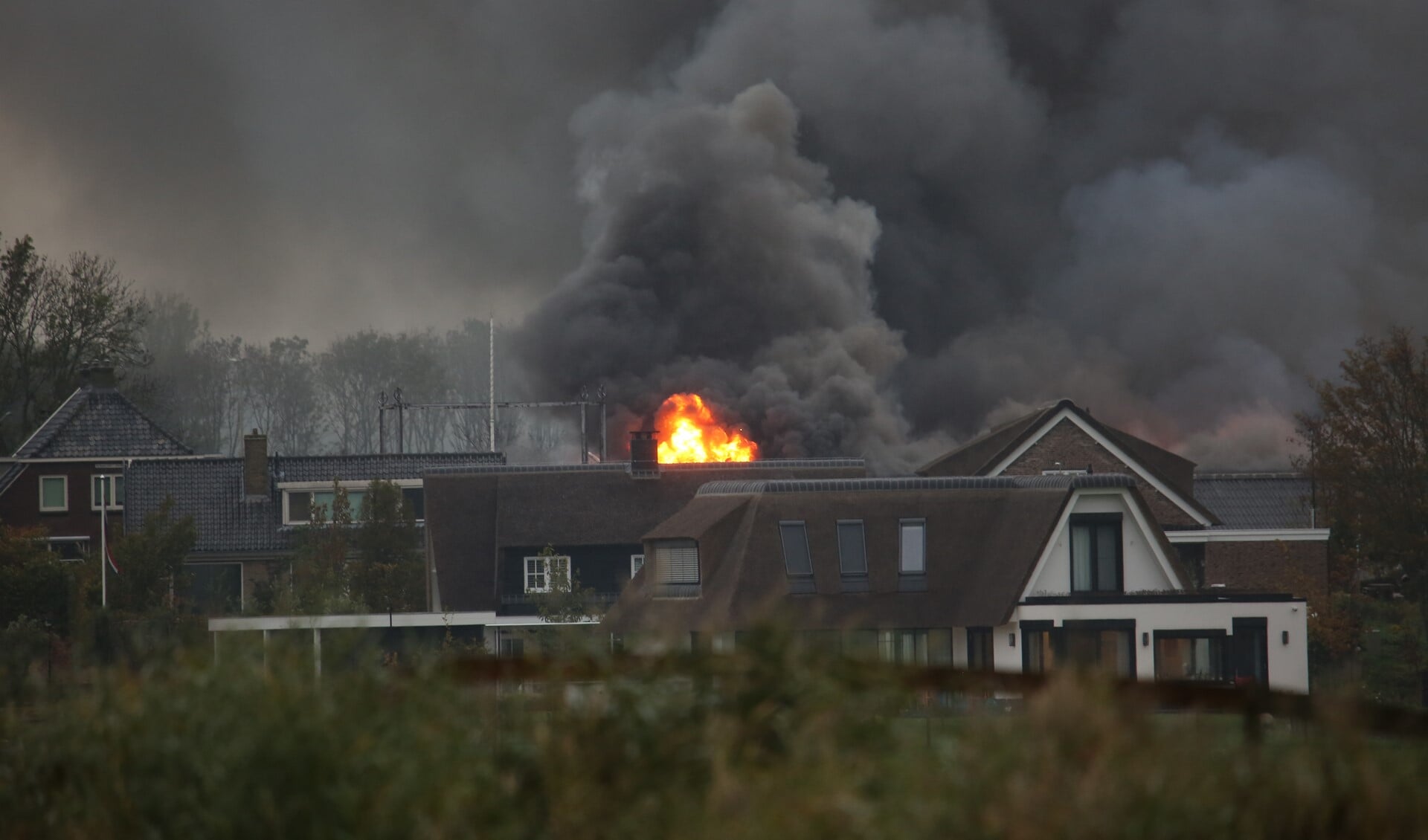 Een vuurzee en grote vlammen te zien achter de bebouwing in Stompwijk (foto: Roy Wolters/Regio15).