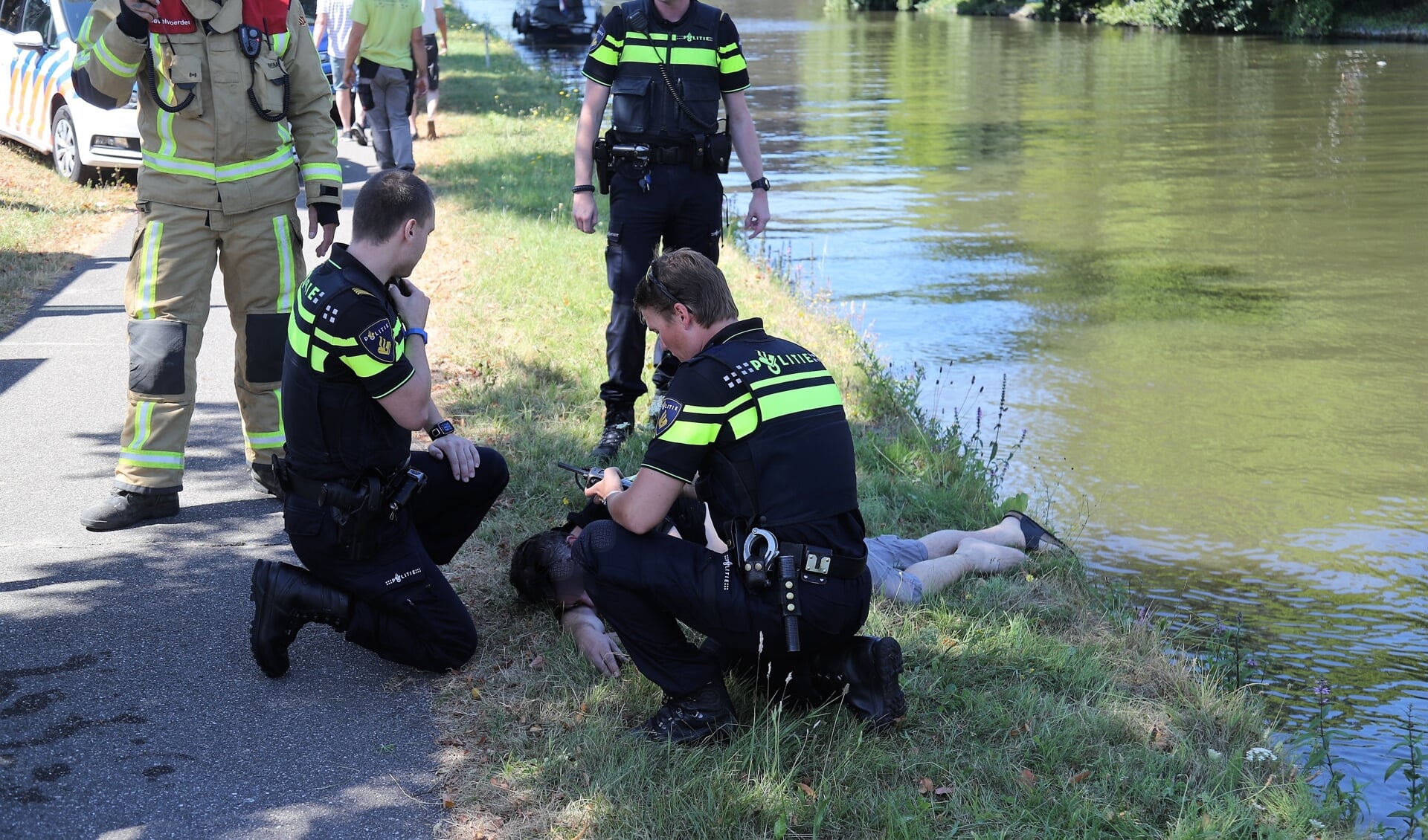 Het slachtoffer ligt bij te komen nadat hij op de kant is geholpen (foto: Rene Hendriks/Regio15).