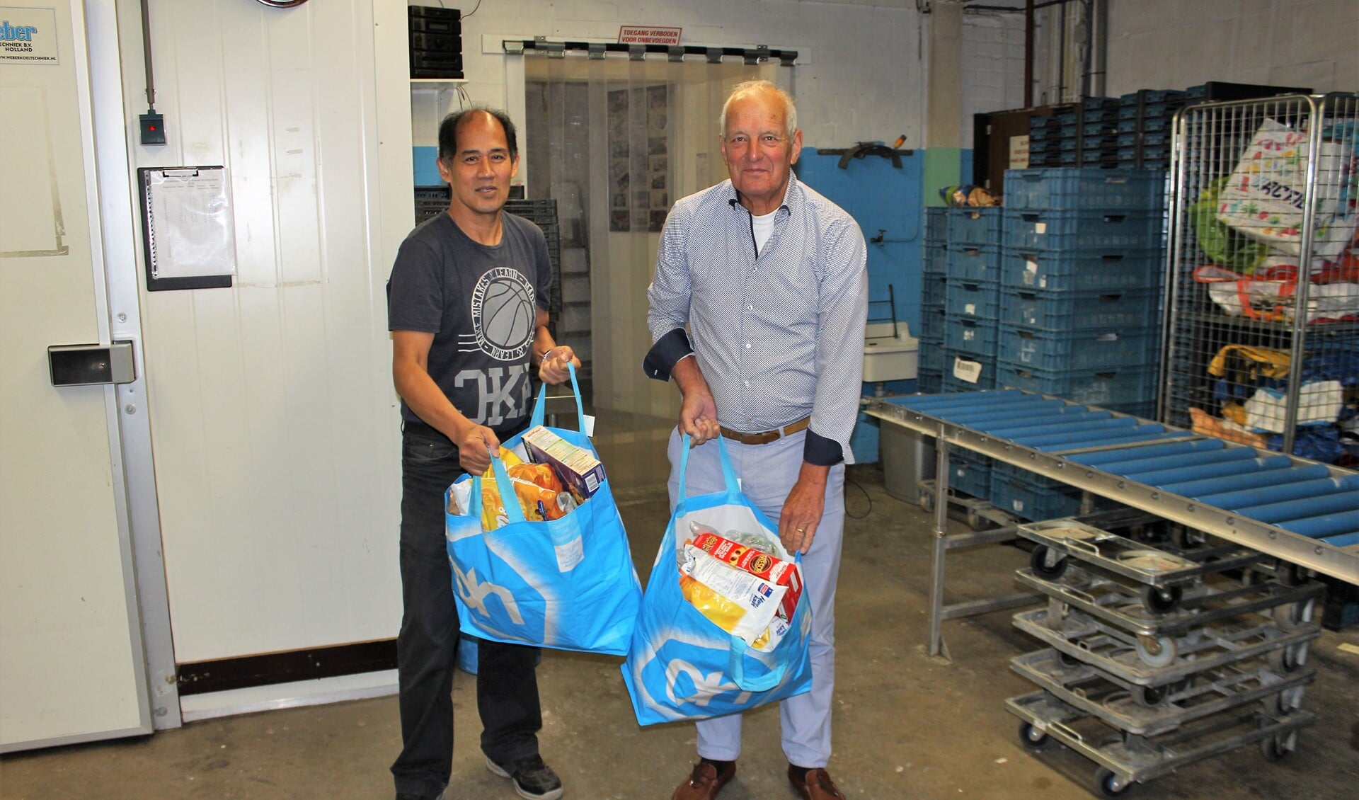 Vrijwilliger Jim met voorzitter Nan de Smet (r.) van de Stichting Buren met een voedselpakket dat naar de klanten gaat (foto: DJ).