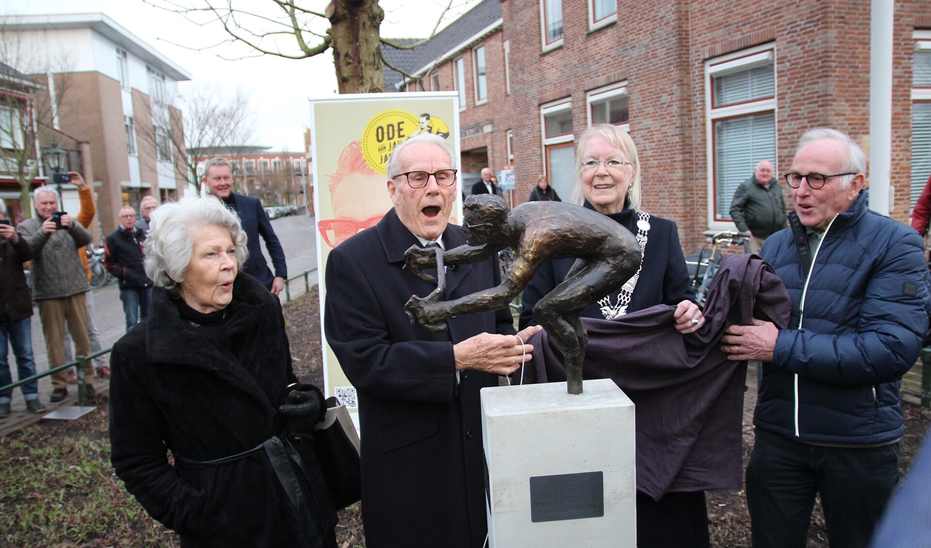 Jan Janssen juicht bijna als hij het beeld onthuld heeft. Echtgenote Cora (links), de burgemeester en Joop Zoetemelk zijn ook blij verrast.