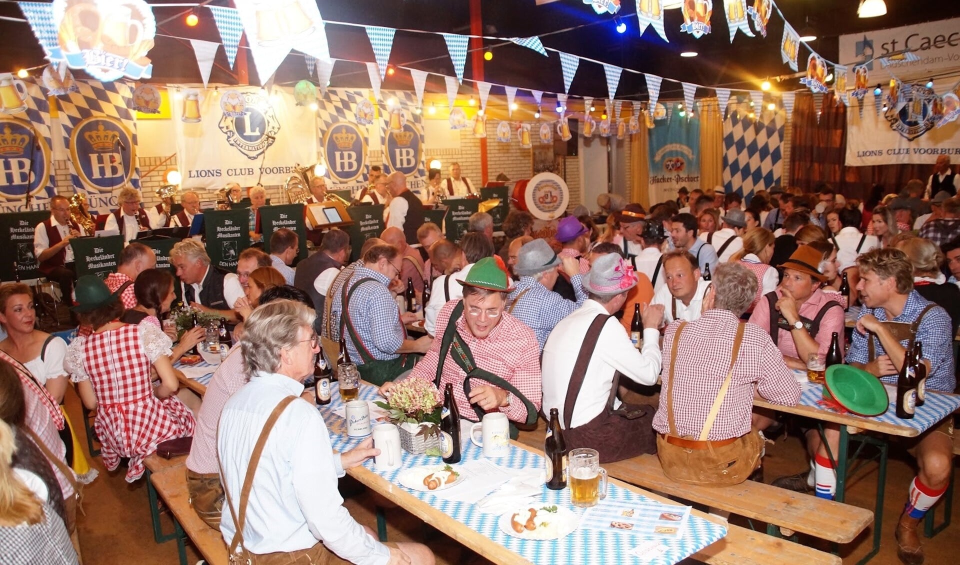 Impressie van het feest met de traditioneel verklede gasten aan lange tafels met bierpullen en Bratwurst (foto: pr).
