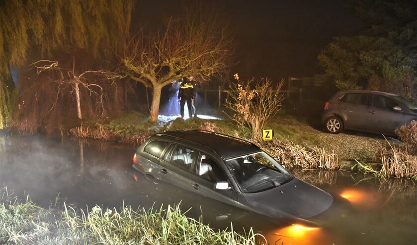 De personenauto drijft in afwachting van de berger nog enigszins rond in de sloot aan het Wilsveen in Leidschendam (foto: Sebastiaan Barel).