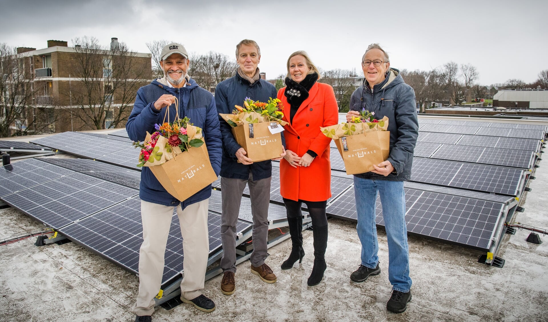 Astrid van Eekelen deelt een bloemetje uit aan de energiecoöperatie Zon op LV om het feestelijke feit te vieren dat het eerste coöperatieve zonnestroomproject in Leidschendam-Voorburg is gerealiseerd (Foto: Paul Voorham).