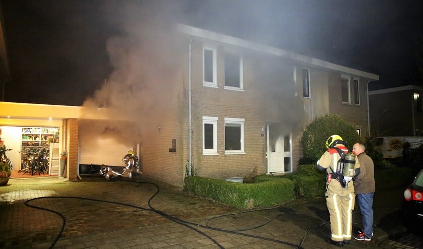 Rookwolken komen uit de garage en het woonhuis, als gevolg van een brand in de garage door een oververhitte schoorsteen van een gaskachtel (foto: Roy Wolters / Regio 15).