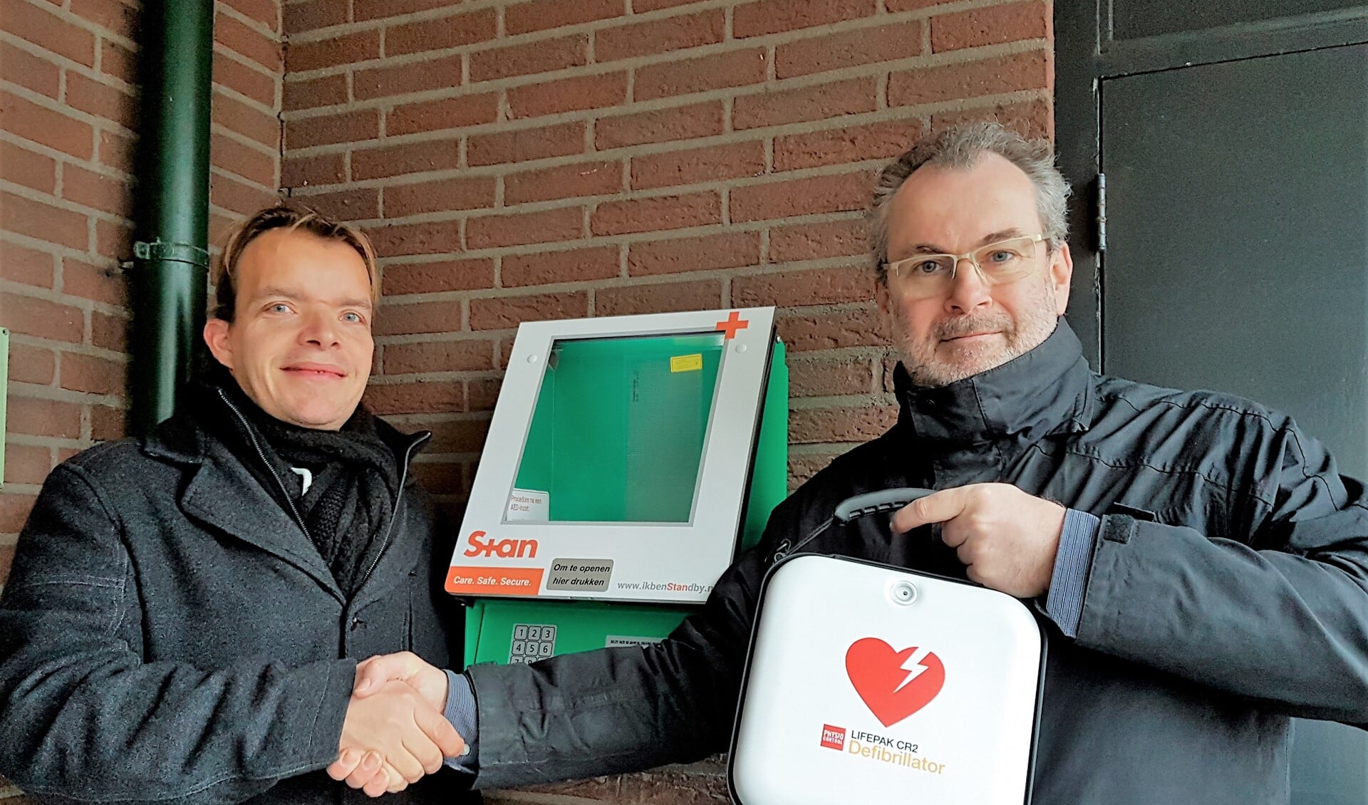 Wouter Verbeek van RLT Nederland (l.) en Adrey Caljé van het bestuur van VvE De Populier met de AED (foto: pr).