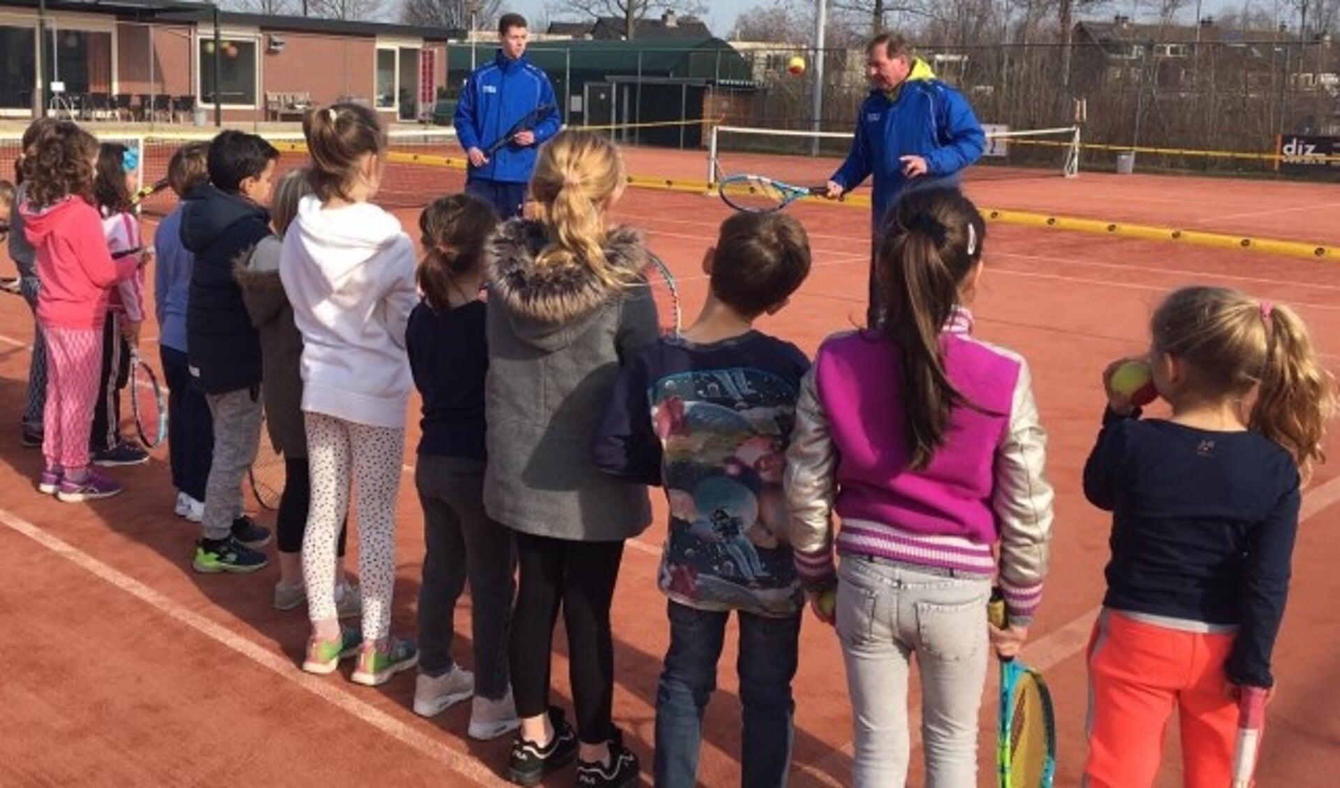 Leerlingen krijgen uitleg van professionele tennisleraren.