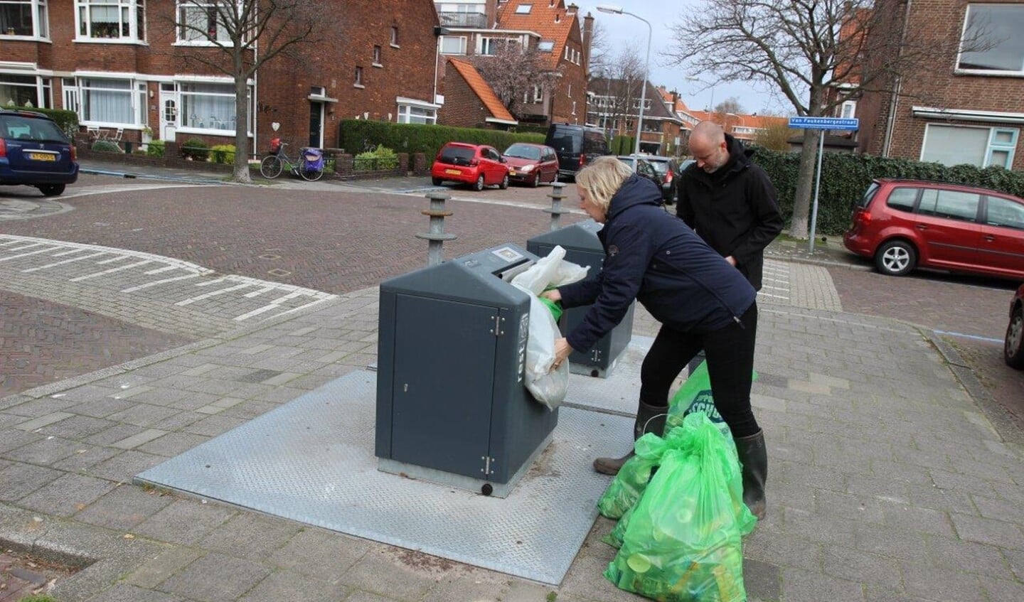 Wethouder Van Eekelen propt de zakken met zwerfafval in de container (foto: Ap de Heus).