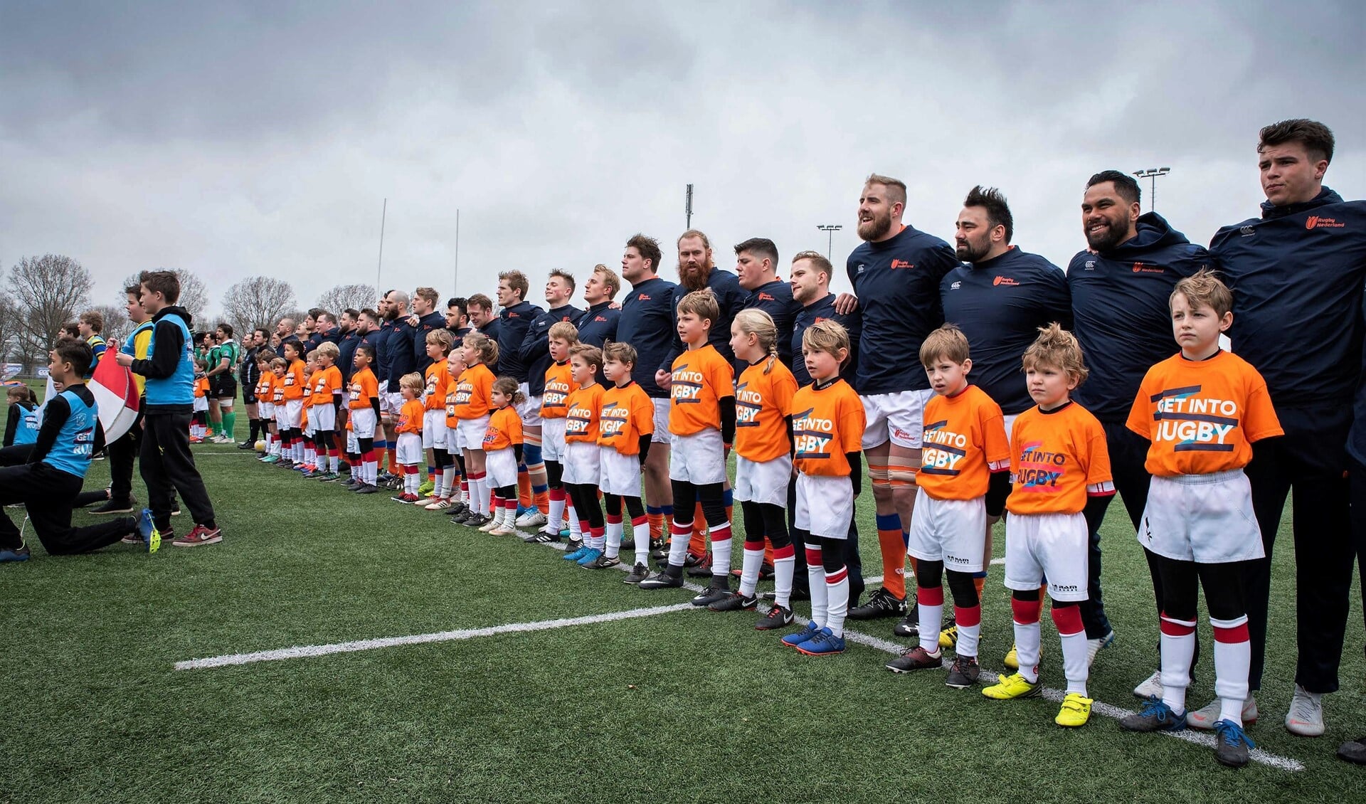 De jeugdleden als player escorts bij de rugbyspelers van het Nederlandse en het Portugese rugyteam (foto: pr VRC).