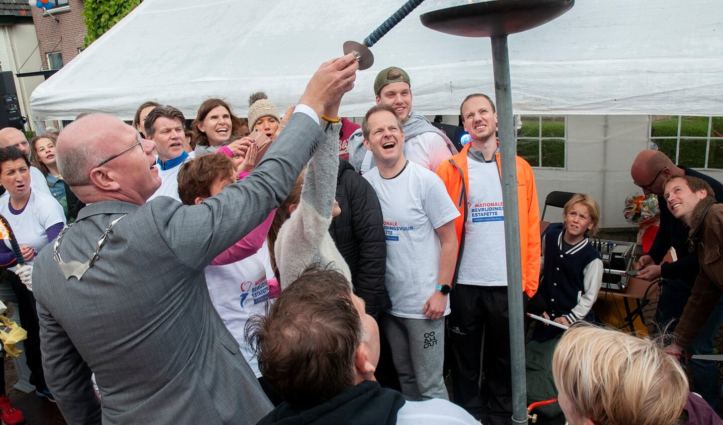 Burgemeester Klaas Tigelaar ontsteekt samen met een van de loopsters het Bevrijdingsvuur in Oranjelust (foto: Michel Groen).