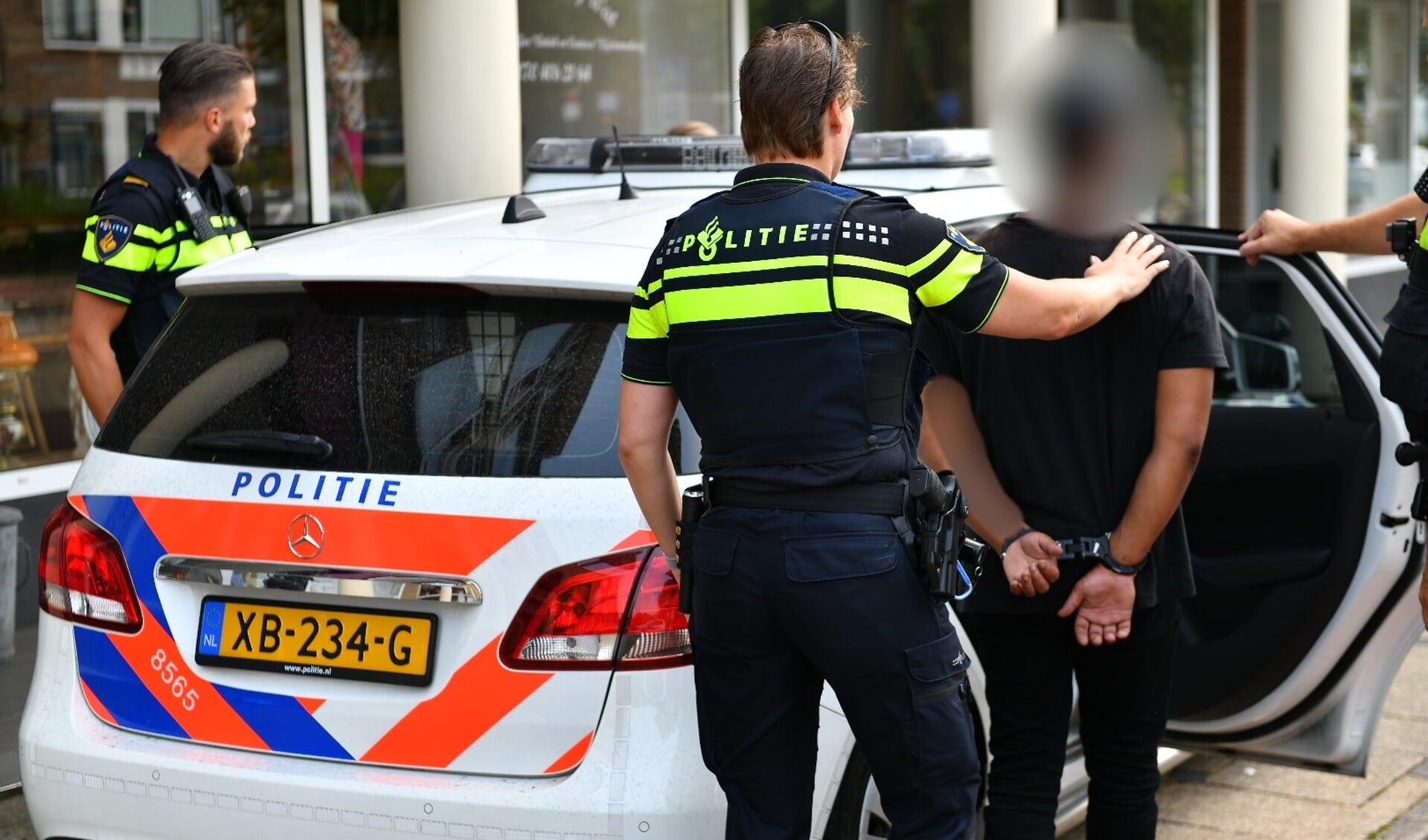 Een van de arrestanten wordt door de politie weggeleid en in een politieauto naar het bureau vervoerd voor ondervraging (foto: Bob van Keulen).