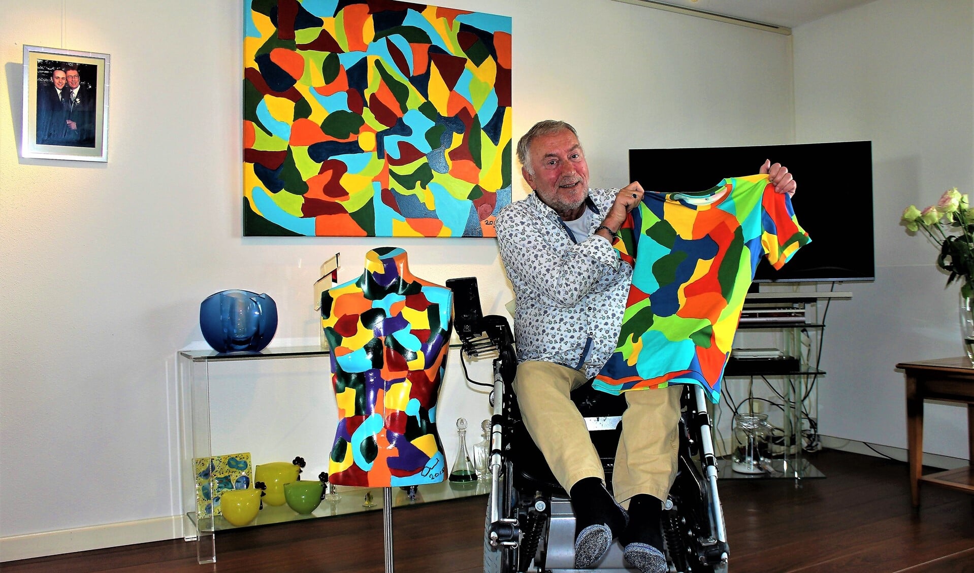 Gerard de Gier met een T-shirt met zijn kleurenpatroon, achter zich een schilderij en naast zich een beschilderde torso (foto/tekst: Dick Janssen).