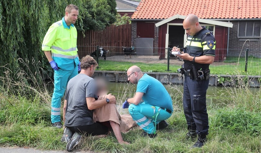 De passant en ambulancemedewerkers ontfermen zich over de man, terwijl de politie gegevens noteert (foto: Rene Hendriks).
