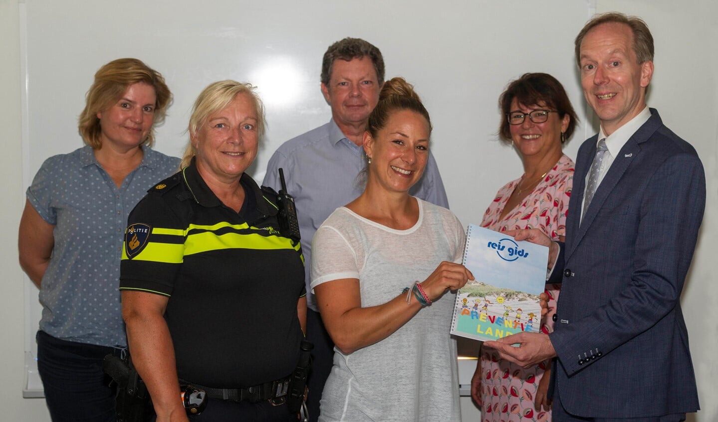 wethouder Jan-Willem Rouwendal (welzijn) neemt het eerste exemplaar van de 'Reis Gids Preventieland' in ontvangst.