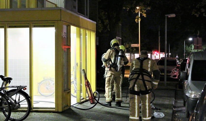 Brandweerlieden actief bij een van de portieken die vol rook hingen (foto: Herman van der Woude).