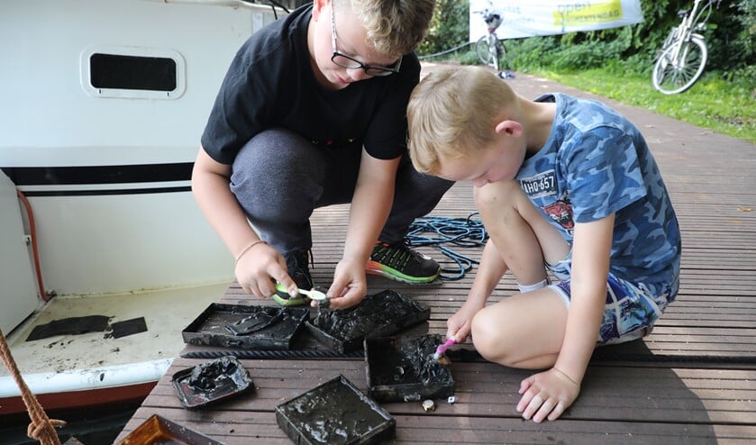 Met een tandenborstel maken de jongens de sieraden schoon. (Foto: Regio15/Donny Kooistra)
