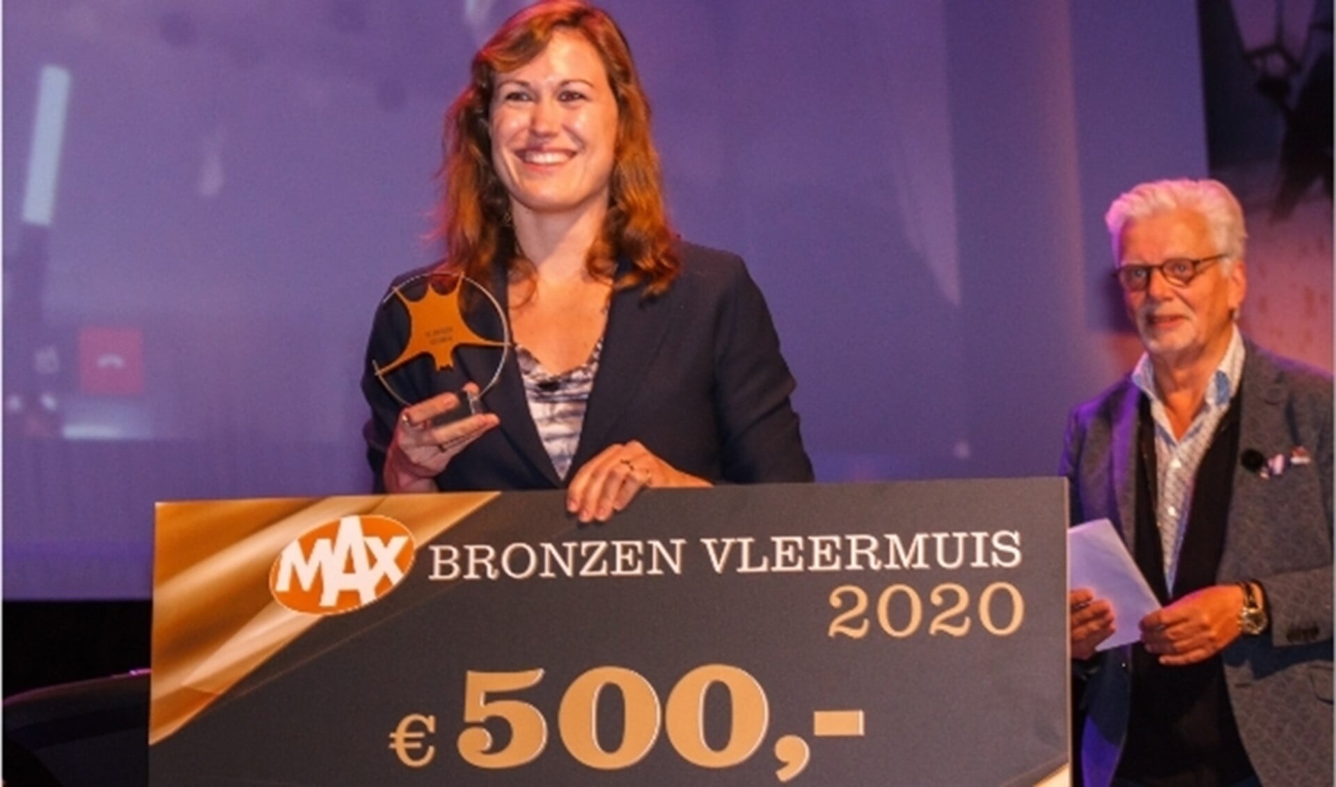 Vertegenwoordigster van de uitgeverij van Mohlin & Nyström neemt de bronzen vleermuis in ontvangst. 