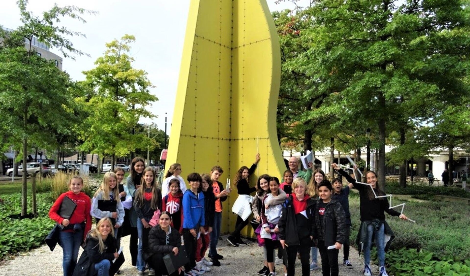 Een grote groep kinderen leek een reusachtig beeld te omarmen op het Stationsplein in Voorburg (foto: Ap de Heus).