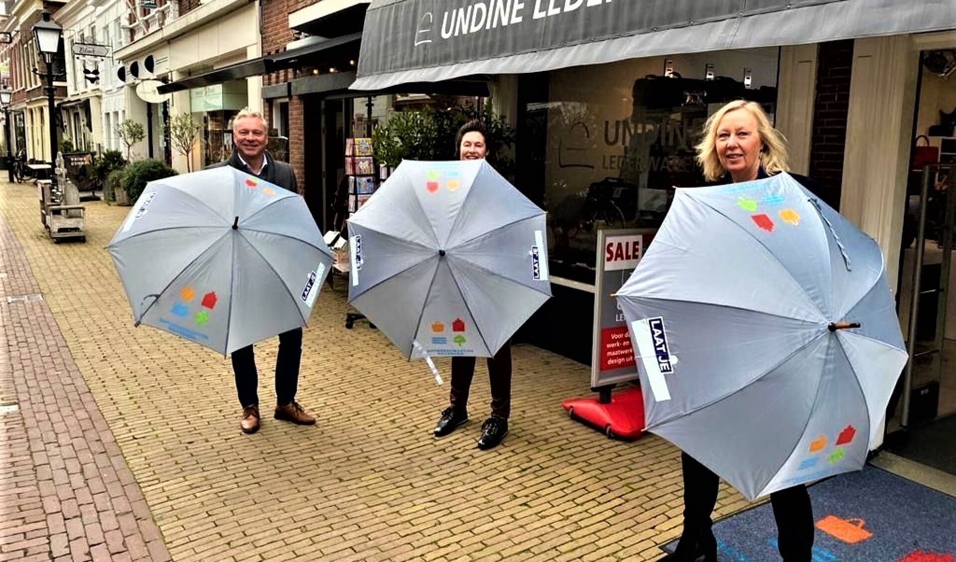 Undine Eckardt van Undine Lederwaren ontvangt de eerste paraplu’s met boodschap ‘laat je verrassen in Huygenskwartier’ van Astrid van Eekelen en Edwin Marijs, voorzitter van ondernemersfonds Huygenskwartier (foto: gemeente LV).
