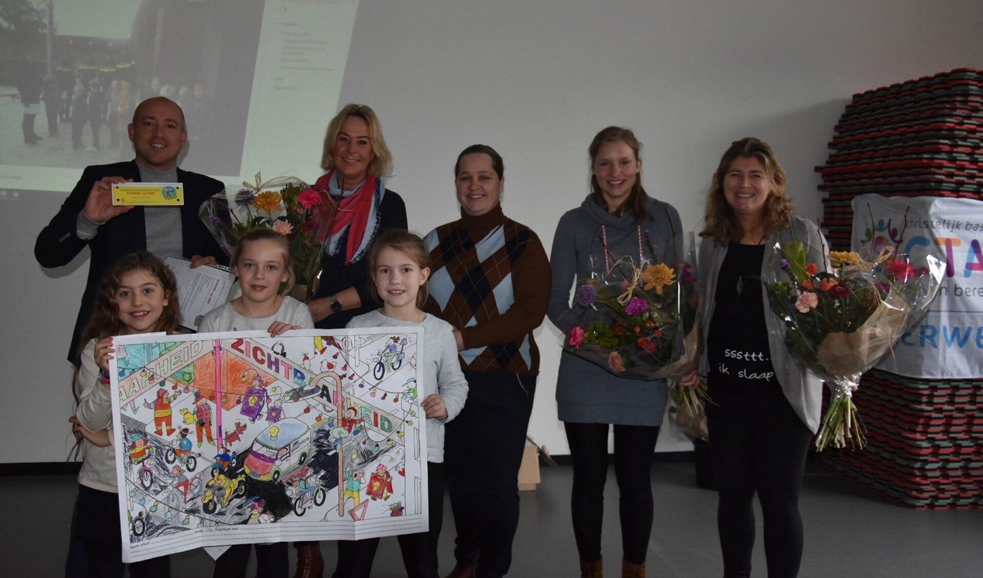 Op de foto directeur Robin van Eekert, managementassistente Annelies Feenstra, wethouder Ilona Jense, Maaike van den Berg en Wendy Holtzapfel. Vooraan leerlingen met tekentalent. 