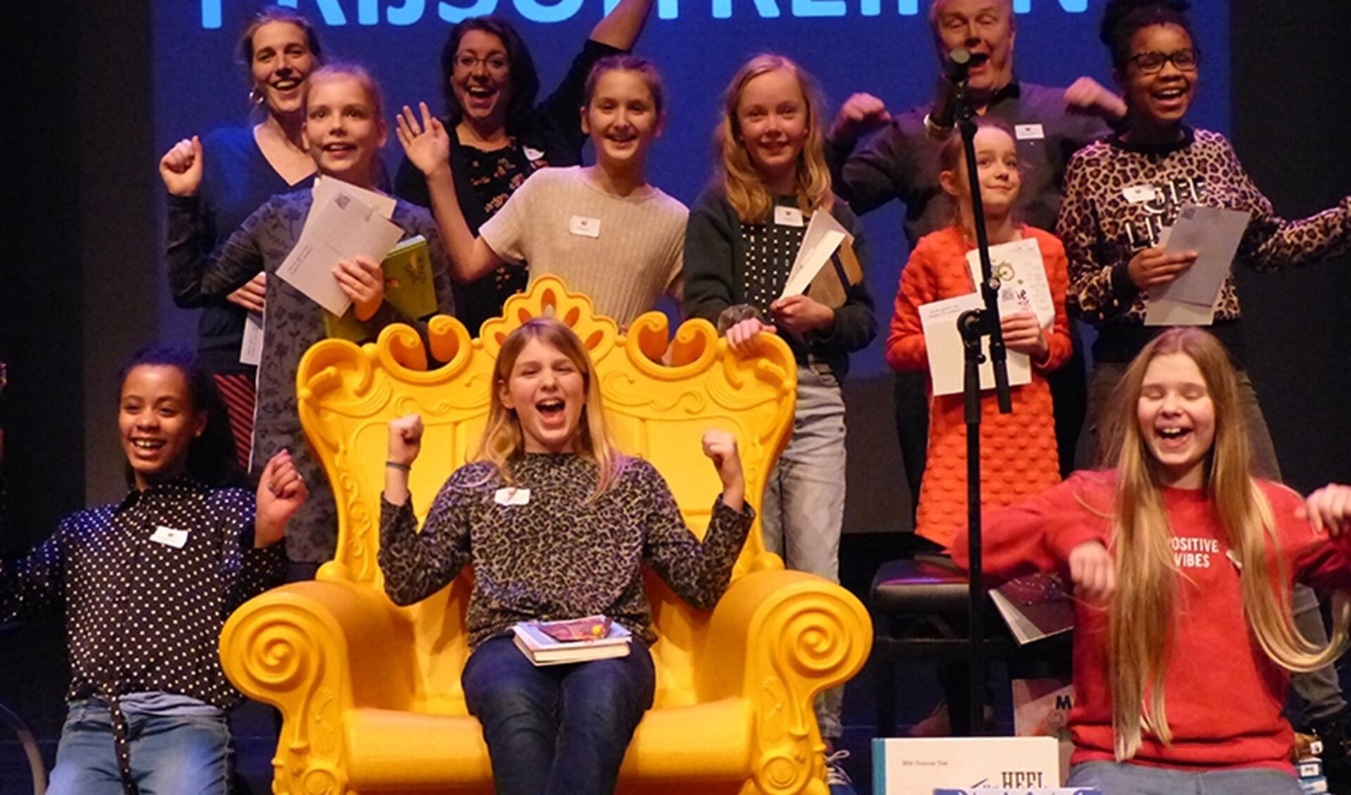 Alle deelnemers en juryleden met de winnende Caja in de gele voorleestroon (foto: Bibliotheek aan de Vliet).