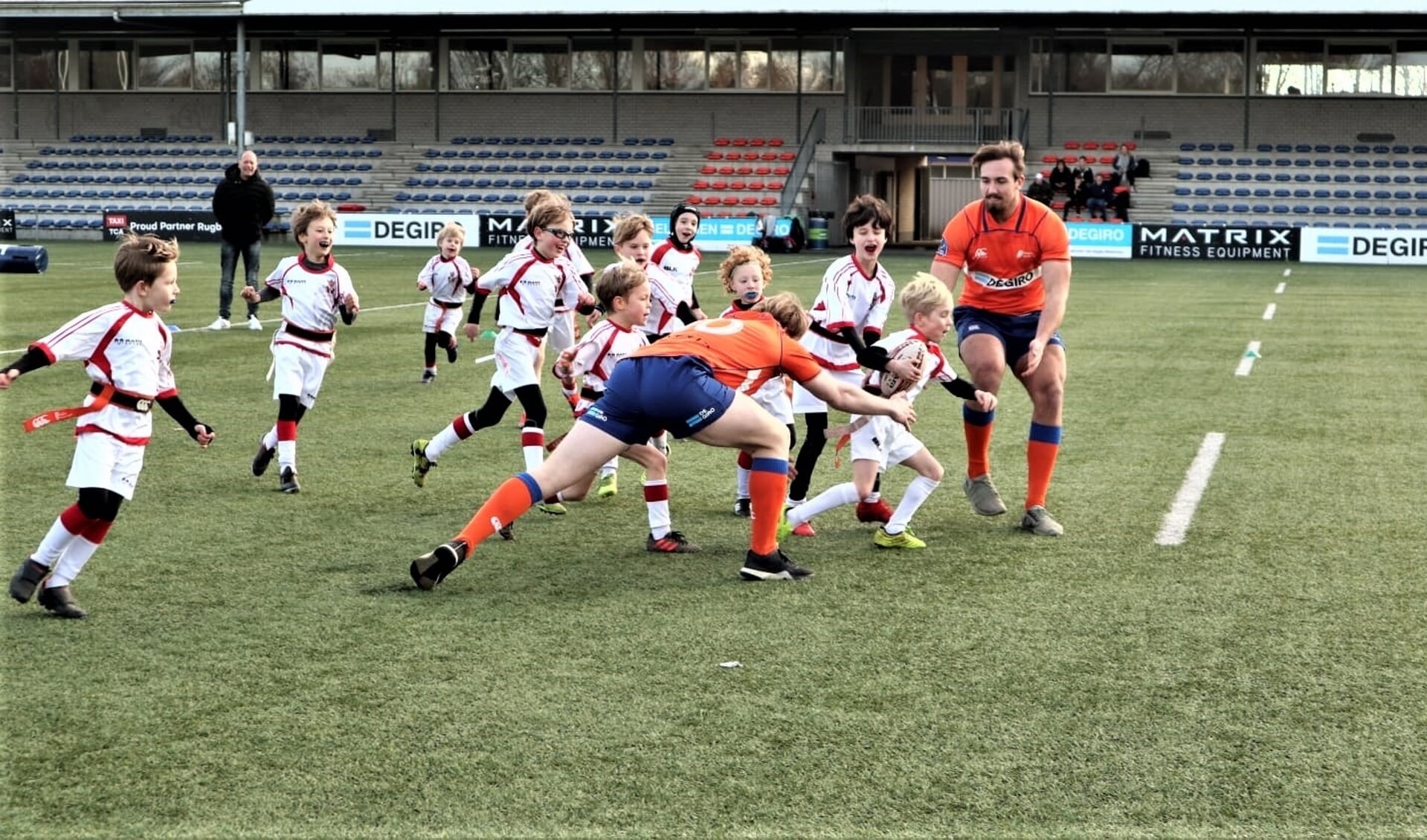De rugby internationals worden belaagd door een horde jonge spelers van VCC (foto: Wietske de Jong).