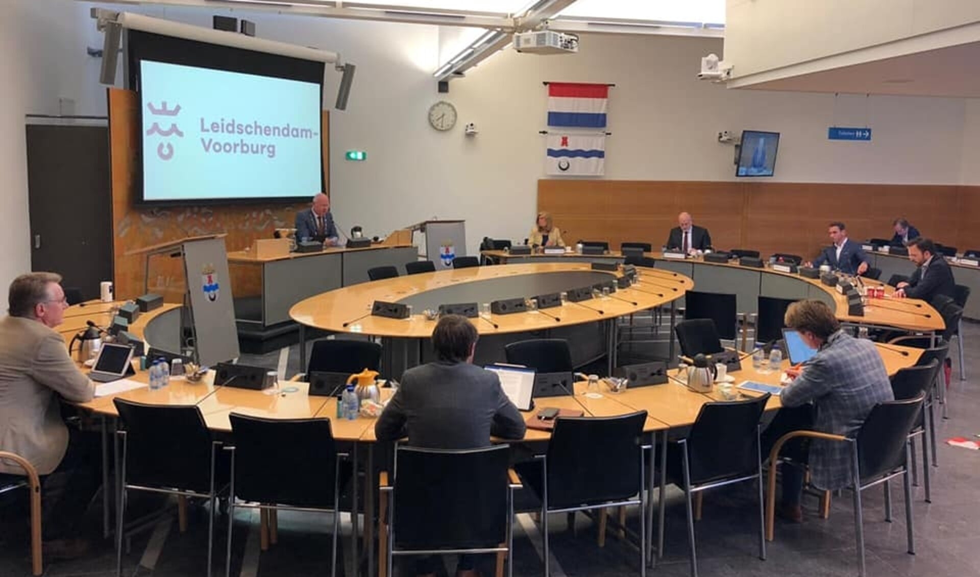 Een gemeenteraadsvergadering met de vertegenwoordigers van de politieke partijen op ruime afstand van elkaar (foto: gemeenteraad LDVB).