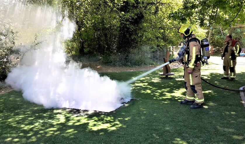 Een brandweerman blus de resten van de trampoline in de speeltuin af (foto: Sebastiaan Barel/Regio15).