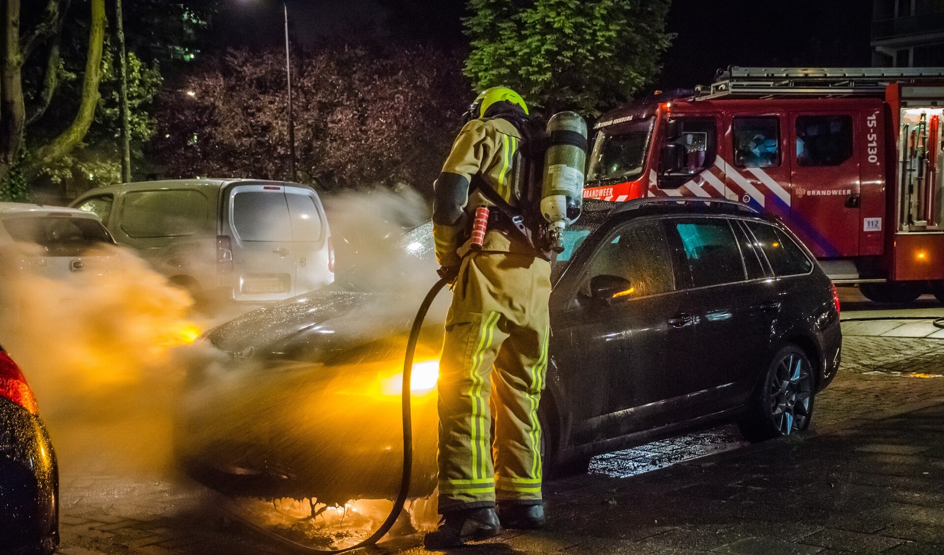 Een brandweerman blust de brandende auto af (foto: Sebastiaan Barel/Regio15).